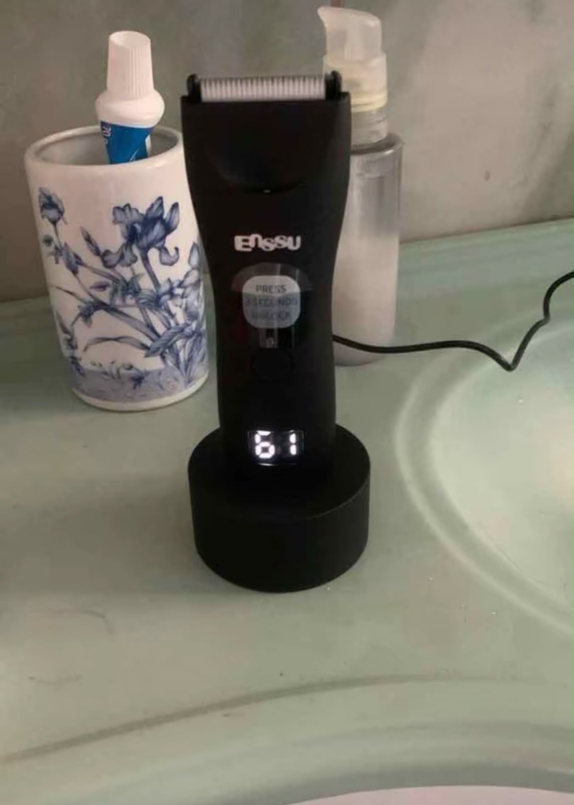 ENSSU Pro na base, na pia do banheiro, display mostrando 61